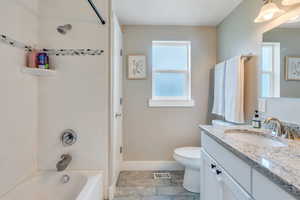 Full bath featuring bathtub / shower combination, vanity, toilet, and baseboards