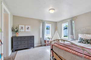 Bedroom with carpet, a textured ceiling, and baseboards