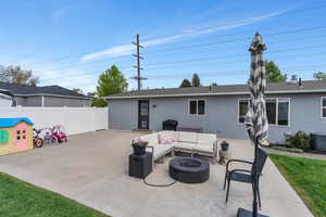 Rear view of house featuring a patio area, stucco siding, an outdoor living space with a fire pit, fence, and central AC unit