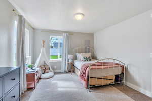 Carpeted bedroom featuring baseboards and a textured ceiling