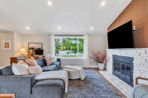 Living room with a fireplace with flush hearth, wood finished floors, recessed lighting, and baseboards