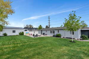 Rear view of house with a patio area, stucco siding, and an outdoor structure