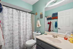 Bathroom with vanity, toilet, and a shower with shower curtain