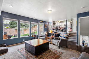 Carpeted living area with a textured ceiling, healthy amount of natural light, and baseboards