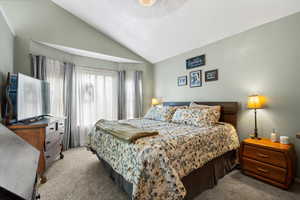 Carpeted bedroom featuring lofted ceiling