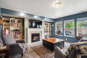 Living room with light carpet, a textured ceiling, and a tile fireplace