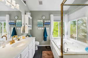 Full bathroom featuring vanity, a jetted tub, toilet, tile patterned flooring, and baseboards