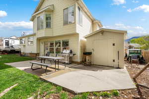 Rear view of house featuring a patio area, a yard, a shed, and a mountain view