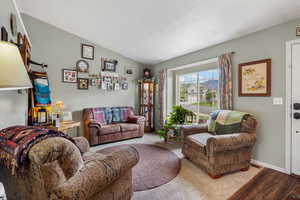 Living area with wood finished floors, vaulted ceiling, and baseboards