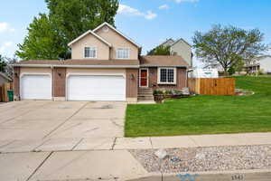 View of front of home with driveway, roof with shingles, brick siding, and a 3 car garage