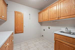 Washroom featuring cabinet space, hookup for a washing machine, hookup for an electric dryer, baseboards, and light tile patterned flooring