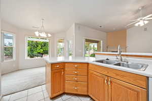 Kitchen featuring light colored carpet, a sink, light countertops, and healthy amount of natural light