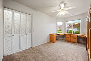 Unfurnished office featuring light colored carpet, a ceiling fan, and baseboards