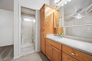 Bathroom with ceiling fan, vanity, a stall shower, toilet, and baseboards