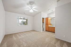 Unfurnished bedroom with light carpet, lofted ceiling, baseboards, connected bathroom, and a sink