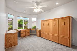 Unfurnished office with light colored carpet, ceiling fan, recessed lighting, built in desk, and baseboards