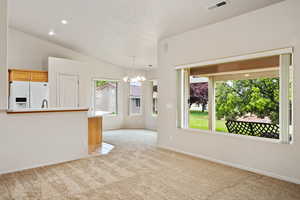 Unfurnished living room featuring a chandelier, light carpet, baseboards, vaulted ceiling, and recessed lighting