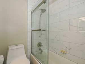 Bathroom featuring toilet and enclosed tub / shower combo