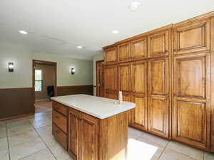 Kitchen featuring brown cabinets, light tile patterned flooring, a center island, recessed lighting, and light countertops