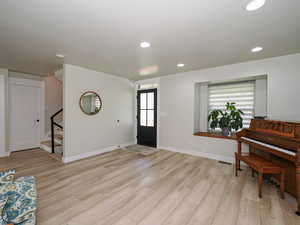 Foyer featuring stairs, light wood finished floors, recessed lighting, and baseboards