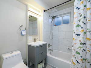 Bathroom featuring shower / tub combo with curtain, vanity, and toilet
