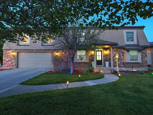 Traditional-style house featuring concrete driveway, a front lawn, stone siding, stucco siding, and a garage