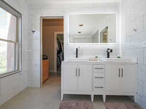 Bathroom featuring double vanity and a walk in closet