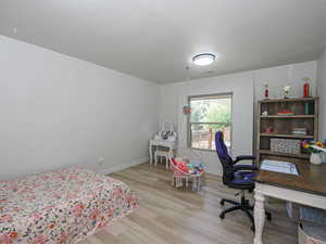 Bedroom with wood finished floors, baseboards, and an office area