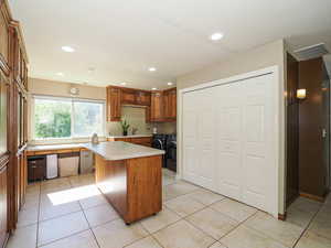 Kitchen featuring washing machine and dryer, light countertops, a sink, recessed lighting, and light tile patterned flooring