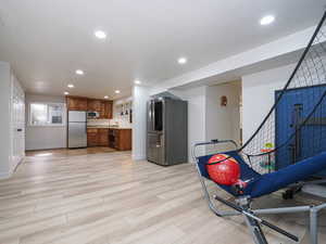 Kitchen with appliances with stainless steel finishes, brown cabinetry, recessed lighting, light wood-style flooring, and baseboards