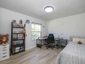 Bedroom featuring wood finished floors, baseboards, and a desk
