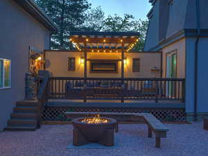 Back of house with an outdoor fire pit, a wooden deck, and stucco siding