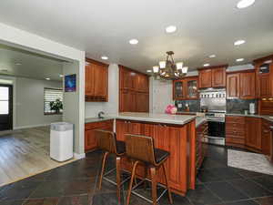 Kitchen with electric stove, glass insert cabinets, recessed lighting, baseboards, and a chandelier