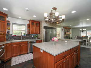 Kitchen with appliances with stainless steel finishes, a chandelier, open shelves, a sink, and backsplash