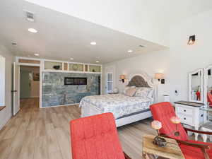 Bedroom featuring recessed lighting, light wood-style flooring, and a multi sided fireplace