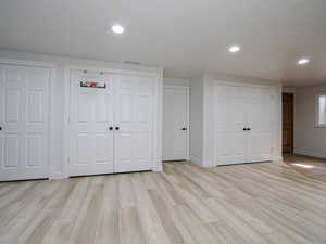 Unfurnished bedroom with multiple closets, baseboards, light wood finished floors, and recessed lighting