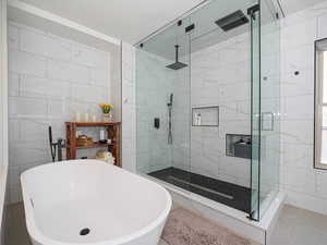 Bathroom featuring a freestanding tub, a shower stall, and tile walls