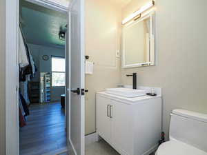 Half bathroom featuring toilet, vanity, and wood finished floors