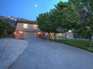 View of front facade with concrete driveway, a garage, a mountain view, central air condition unit, and stucco siding