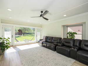 Living area with a ceiling fan, wood finished floors, recessed lighting, and ornamental molding