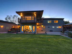 Back of house with a balcony, a patio, and a lawn