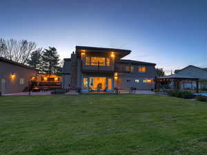 Rear view of property with a gazebo, a lawn, a balcony, and a patio