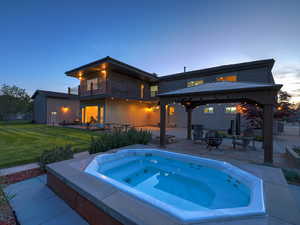 Pool at dusk with a gazebo, an in-ground hot tub, and a patio area