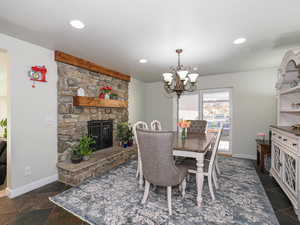 Dining room with a chandelier, baseboards, a stone fireplace, and recessed lighting
