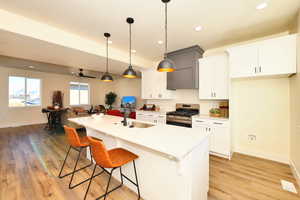 Kitchen with gas stove, a sink, baseboards, a kitchen breakfast bar, and recessed lighting