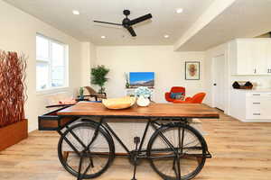 Dining area featuring light wood finished floors, a ceiling fan, a textured ceiling, recessed lighting, and baseboards
