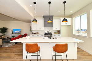Kitchen featuring a sink, light wood-style flooring, a kitchen breakfast bar, white cabinets, and recessed lighting