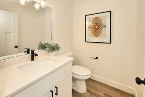 Bathroom with toilet, wood finished floors, vanity, and baseboards