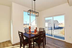Dining area with wood finished floors, a chandelier, baseboards, and plenty of natural light