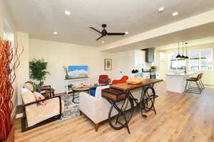 Living area featuring light wood-style floors, a ceiling fan, a textured ceiling, recessed lighting, and baseboards